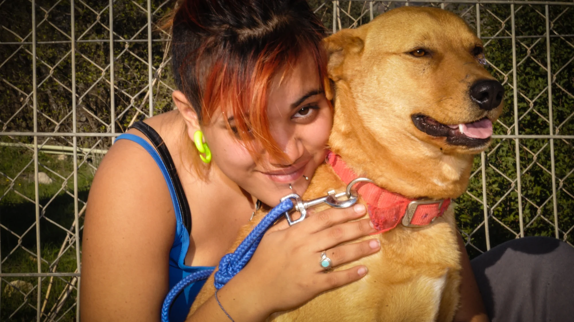 A young person hugging a golden-colored dog at Eshbal