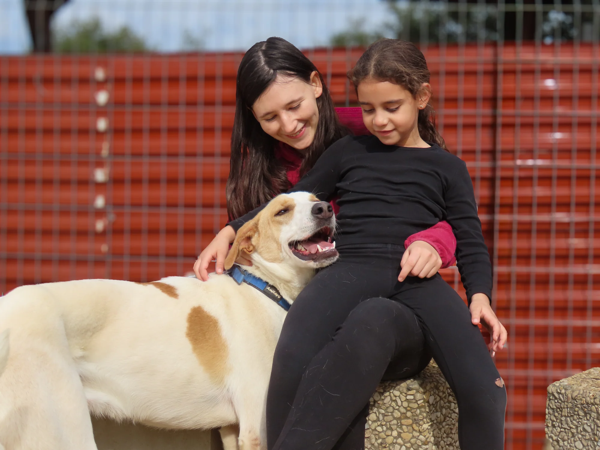 Two young people sharing a gentle moment with a dog at Eshbal